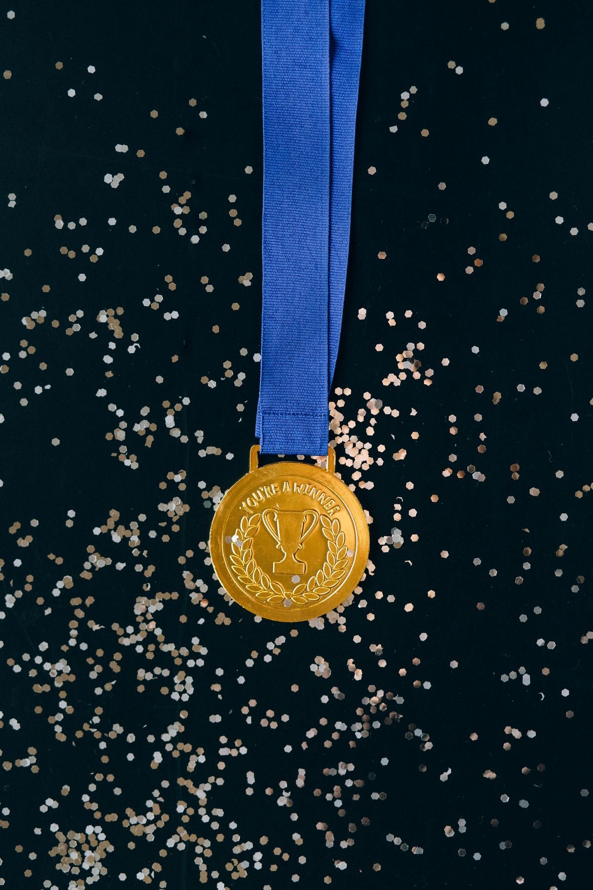 Goldmedaille mit blauem Band, glänzend auf schwarzer Oberfläche
